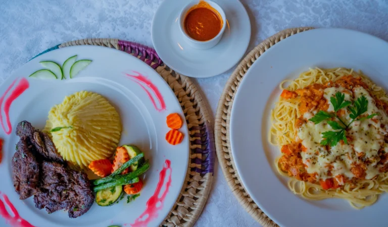 Grilled beef with mash beside cheesy spaghetti, seen from above
