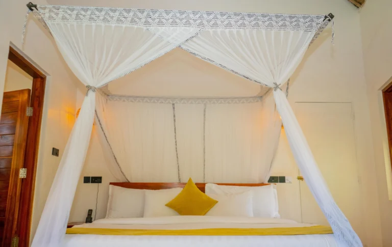 Double bed with mustard cushions under a canopy mosquito net