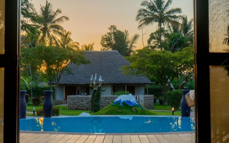 Pool and cottage at sunset through open doors